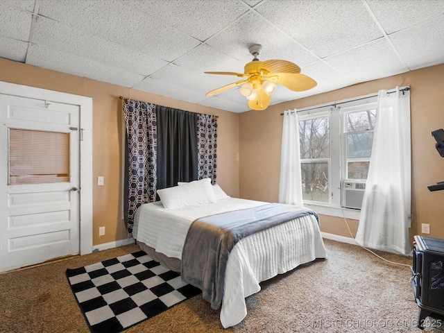 carpeted bedroom featuring a paneled ceiling, cooling unit, baseboards, and a ceiling fan