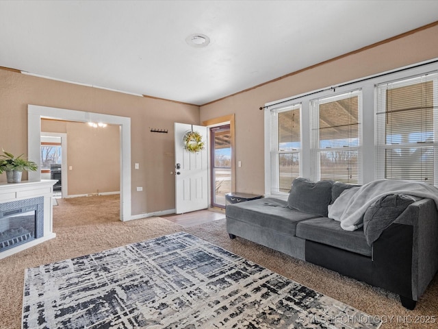 living room featuring baseboards, a tile fireplace, ornamental molding, carpet, and a chandelier