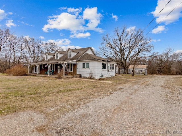 view of front of property with dirt driveway, a front lawn, and a porch