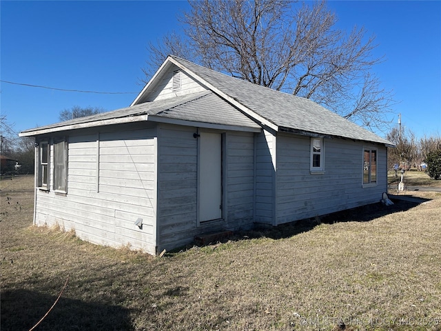 view of property exterior featuring a lawn and a shingled roof