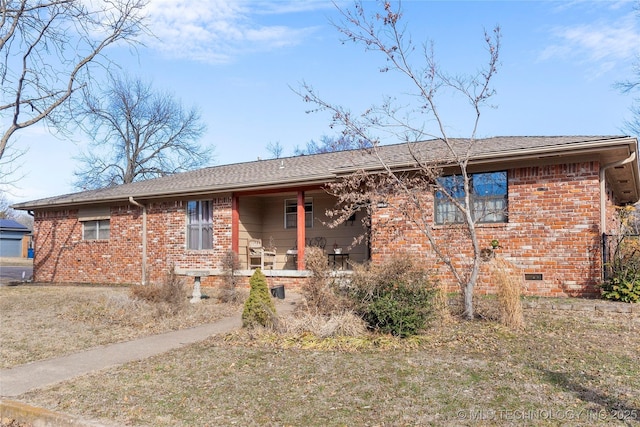 ranch-style house featuring crawl space, a shingled roof, a porch, and brick siding