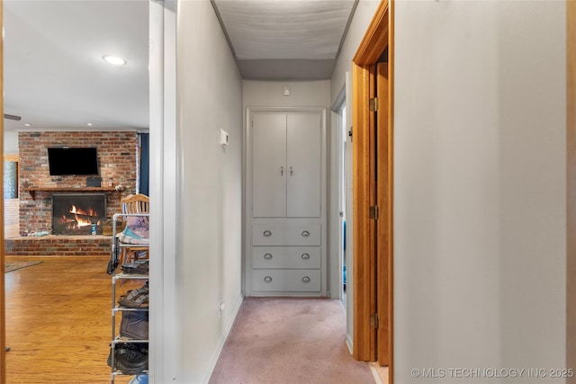 hall featuring light colored carpet and baseboards