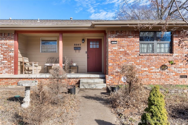 doorway to property with covered porch and brick siding