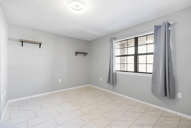 unfurnished room with a textured ceiling and baseboards