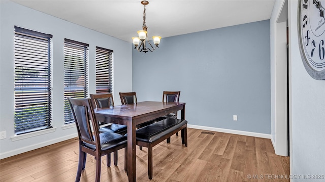 dining room with baseboards, an inviting chandelier, and light wood-style floors