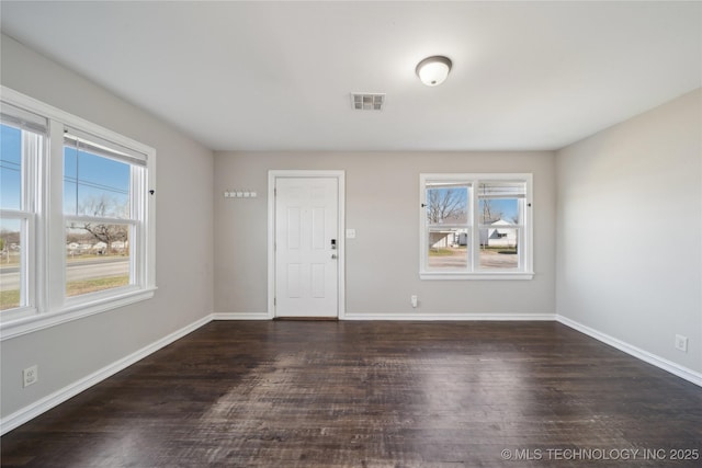 empty room with visible vents, baseboards, and wood finished floors