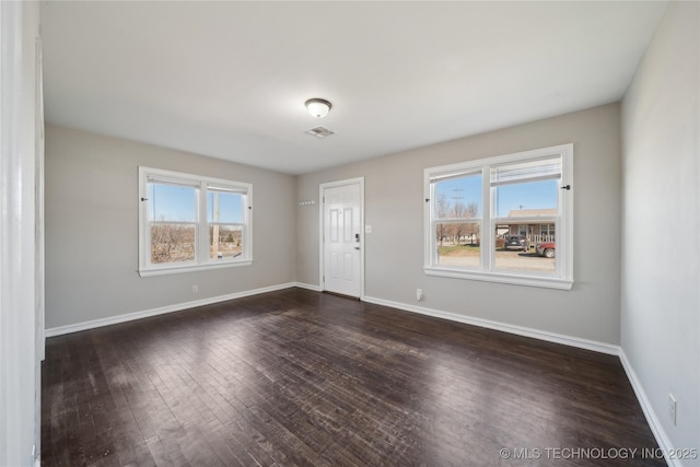 unfurnished room featuring dark wood-style floors, visible vents, and baseboards