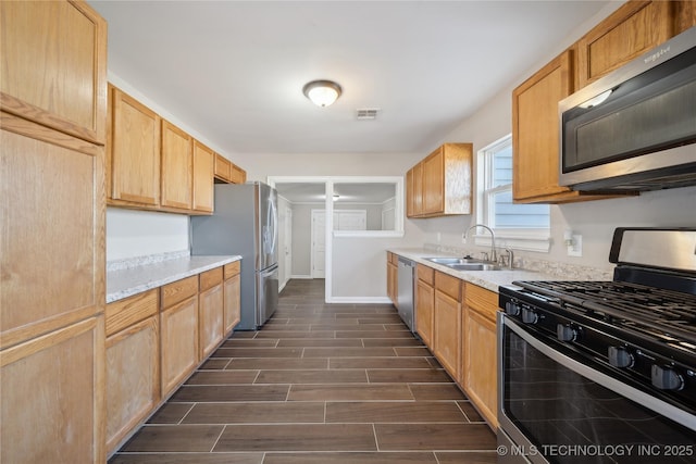 kitchen featuring visible vents, wood finish floors, light countertops, stainless steel appliances, and a sink