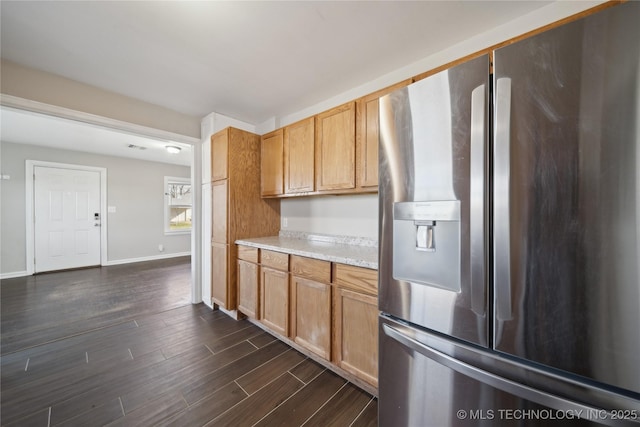 kitchen with dark wood finished floors, light countertops, baseboards, and stainless steel fridge with ice dispenser