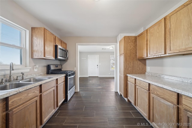 kitchen with a sink, wood finish floors, appliances with stainless steel finishes, and a healthy amount of sunlight