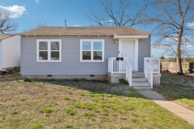 view of front of house with a front yard, fence, roof with shingles, and crawl space