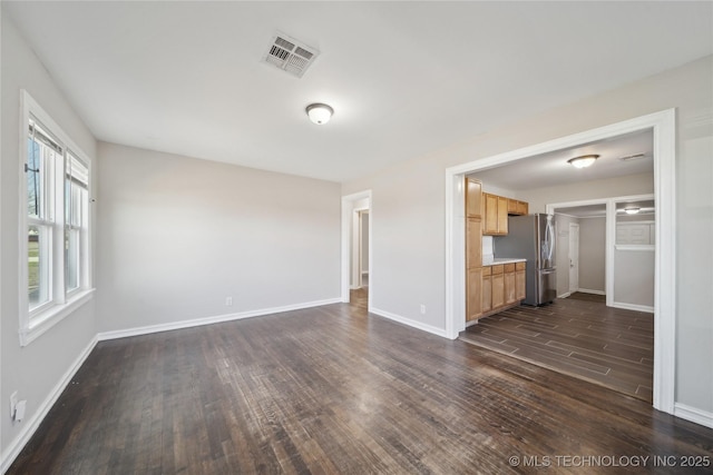 unfurnished living room with dark wood finished floors, baseboards, and visible vents