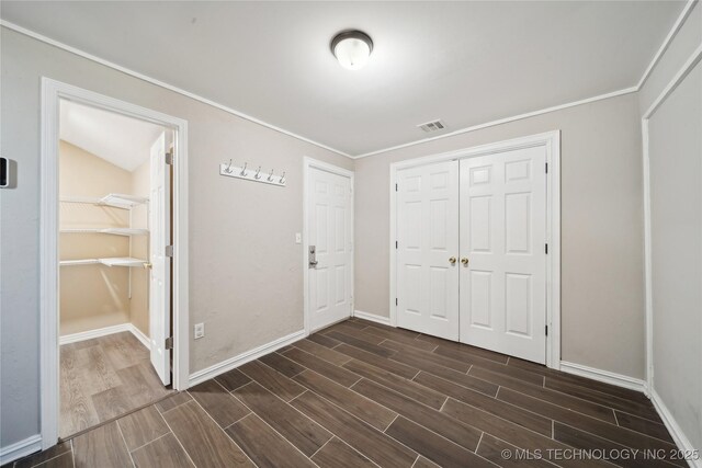 foyer entrance featuring baseboards, visible vents, and wood finish floors