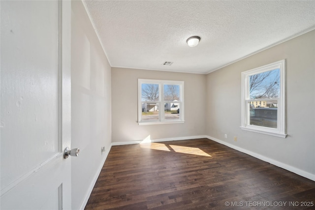 unfurnished room with wood finished floors, visible vents, a wealth of natural light, and baseboards