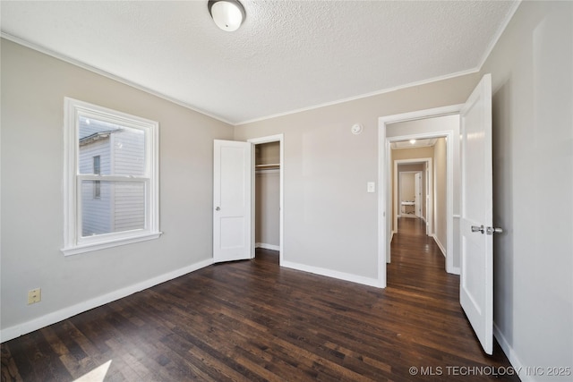 unfurnished bedroom with dark wood-type flooring, baseboards, ornamental molding, a closet, and a textured ceiling