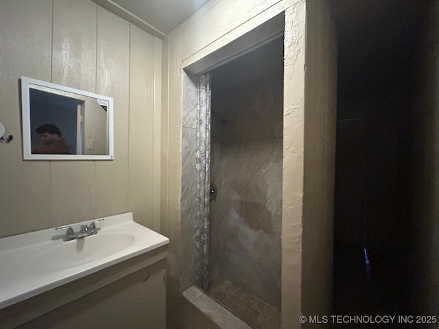 bathroom featuring a tile shower and vanity