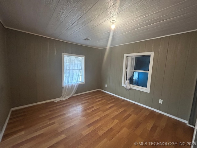 spare room with baseboards, visible vents, and wood finished floors