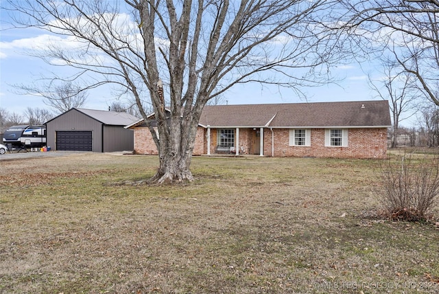 single story home featuring a garage, a front lawn, an outdoor structure, and brick siding