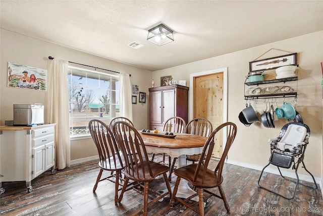 dining space featuring visible vents, dark wood finished floors, a textured ceiling, and baseboards