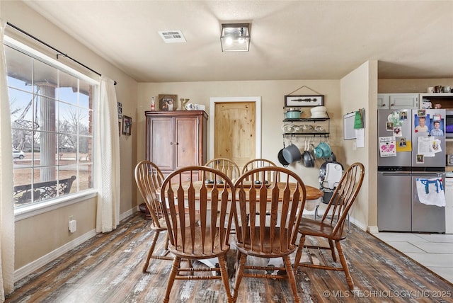 dining room with baseboards, plenty of natural light, visible vents, and wood finished floors