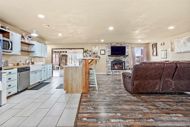 kitchen featuring open shelves, visible vents, stainless steel appliances, and light countertops