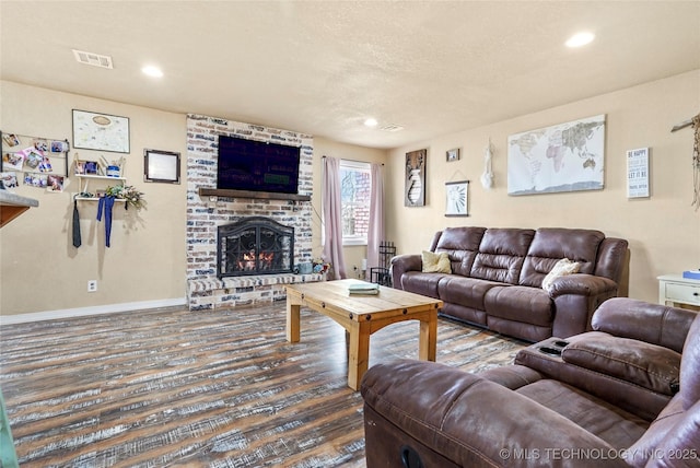 living room featuring recessed lighting, a fireplace, wood finished floors, visible vents, and baseboards