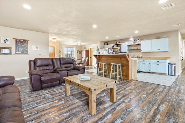 living room with recessed lighting, visible vents, a textured ceiling, and wood finished floors