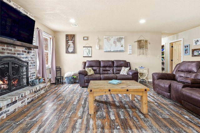 living room featuring baseboards, a fireplace, visible vents, and wood finished floors