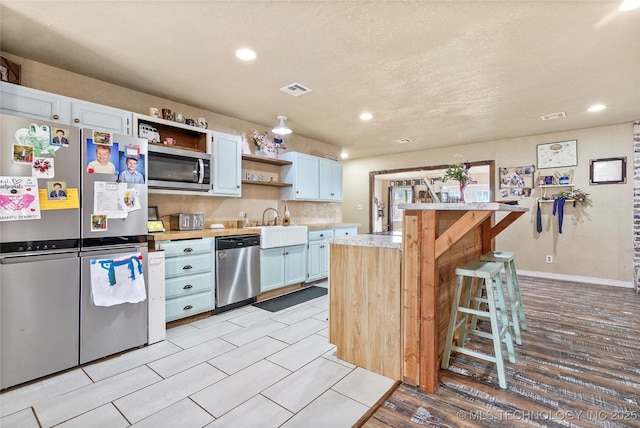 kitchen featuring visible vents, light wood-style floors, light countertops, appliances with stainless steel finishes, and open shelves