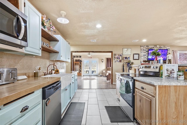 kitchen featuring light countertops, french doors, appliances with stainless steel finishes, backsplash, and open shelves