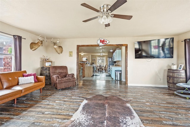 living room featuring a wealth of natural light, ceiling fan, baseboards, and wood finished floors