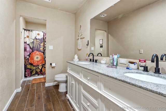 full bathroom with toilet, wood finished floors, a sink, visible vents, and double vanity