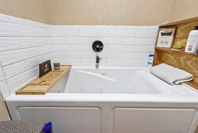 bathroom with a whirlpool tub and a textured wall