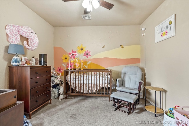 bedroom featuring a nursery area, carpet floors, visible vents, and a ceiling fan