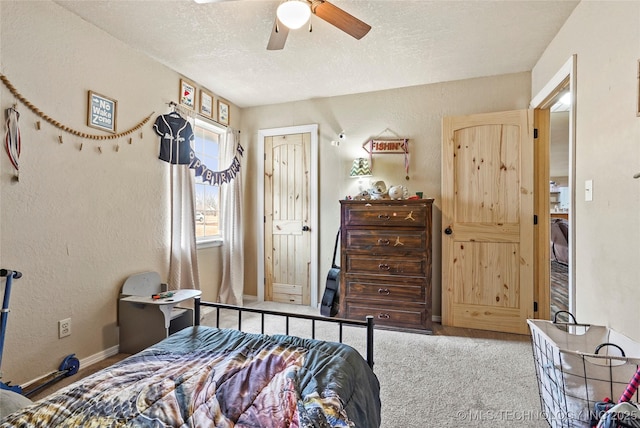 bedroom with baseboards, a textured wall, ceiling fan, carpet flooring, and a textured ceiling