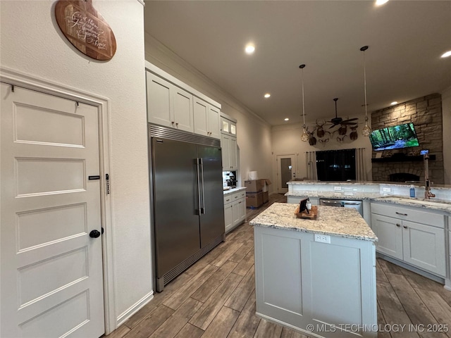 kitchen with light stone counters, recessed lighting, wood finish floors, appliances with stainless steel finishes, and a center island