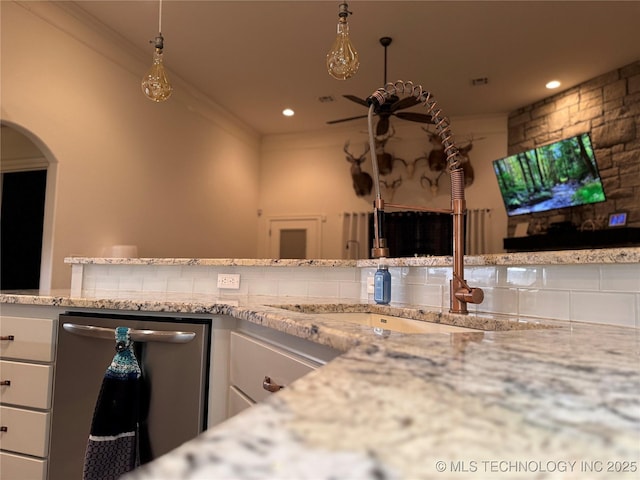 kitchen with a sink, white cabinetry, stainless steel dishwasher, and ornamental molding