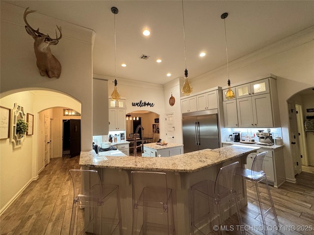 kitchen with a center island, stainless steel built in refrigerator, visible vents, and wood finished floors