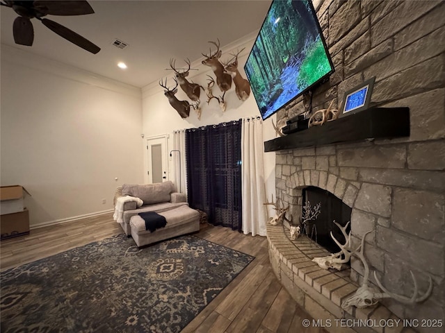 living area with a fireplace, baseboards, crown molding, and wood finished floors