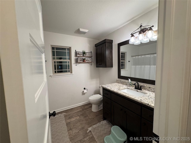 bathroom featuring a textured ceiling, toilet, wood finished floors, visible vents, and vanity