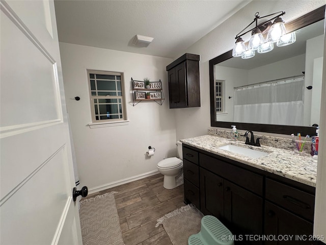 full bath with a textured ceiling, toilet, wood finished floors, vanity, and baseboards