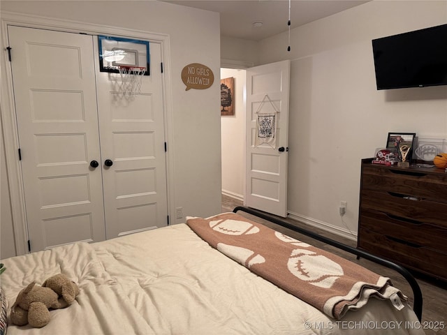 bedroom with a closet, baseboards, and wood finished floors