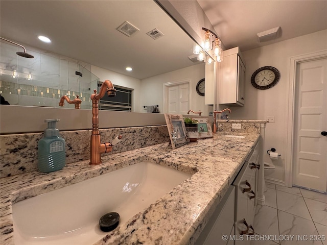 bathroom featuring marble finish floor, visible vents, a tile shower, and a sink