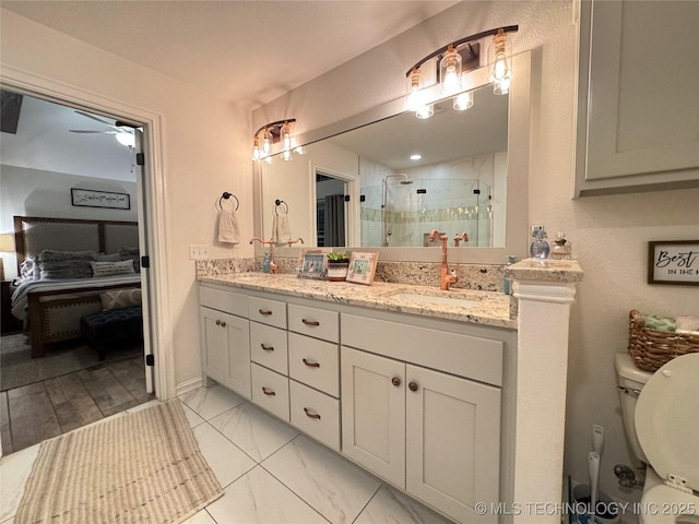 full bathroom featuring marble finish floor, double vanity, a sink, and a shower stall