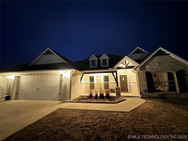 view of front of house with brick siding, a porch, a garage, stone siding, and driveway