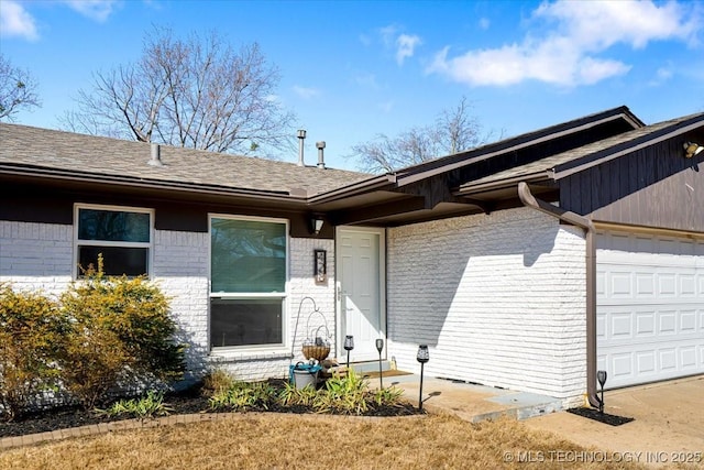 view of front facade featuring a garage, brick siding, roof with shingles, and entry steps