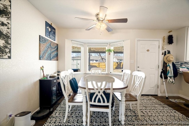 dining area with wood finished floors, a ceiling fan, and baseboards