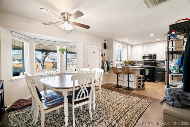 dining space with a ceiling fan, recessed lighting, light wood-style flooring, and baseboards