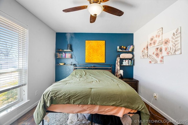 bedroom with ceiling fan, baseboards, and wood finished floors