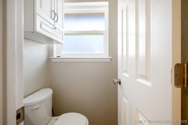 bathroom with a textured wall and toilet